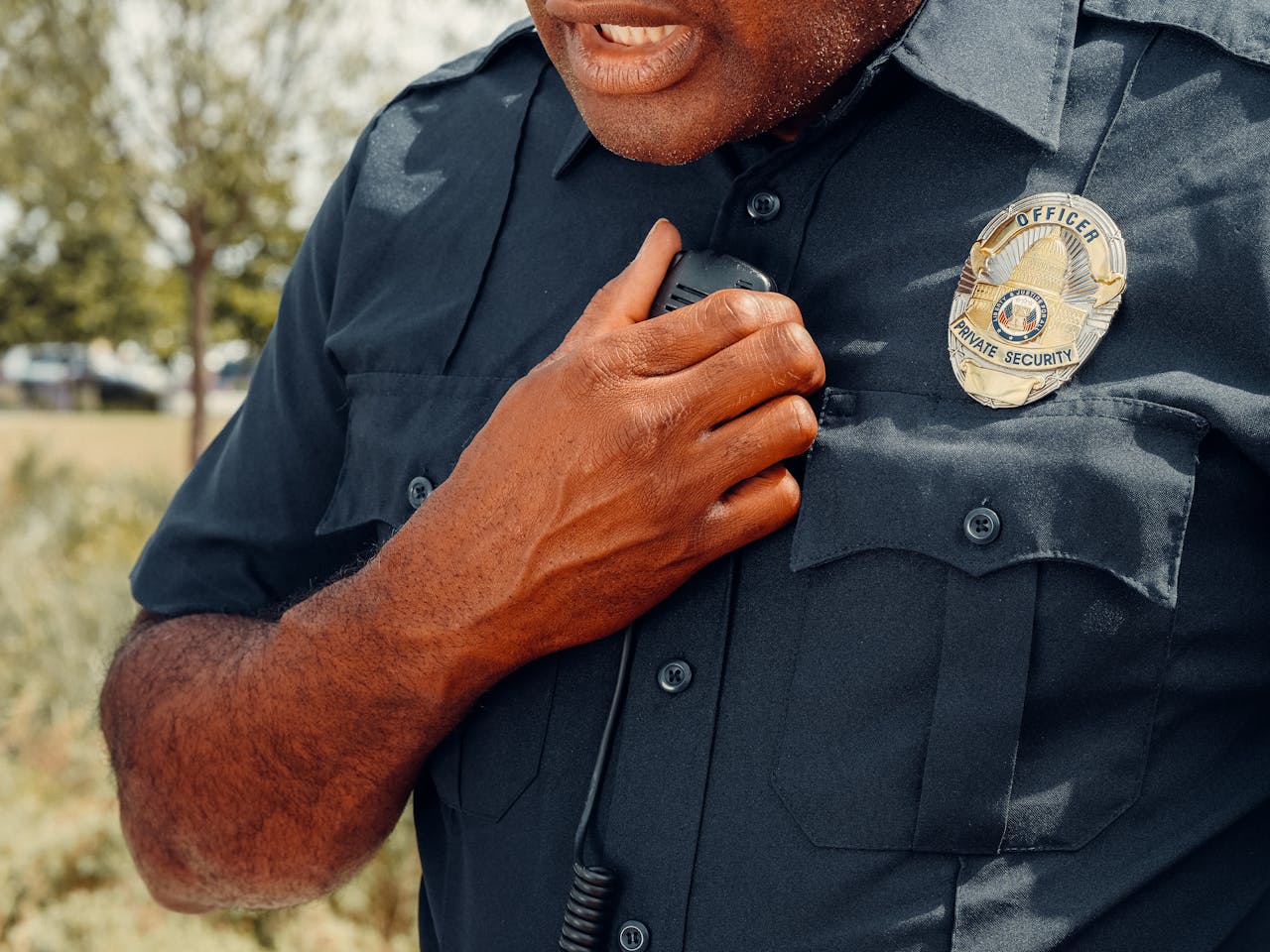 Close-up of a security officer using a radio outdoors, showcasing professional security attire.